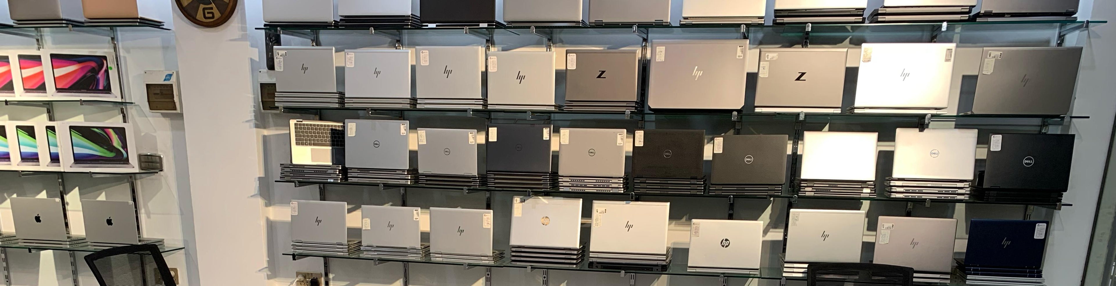 Display of laptops on a counter with brand logos in a store setting